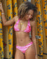 Woman wearing hot pink halter top swimsuit with colorful surfboards in the back.