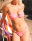 Woman wearing a pink bikini leaning on an orange and white beach chair.