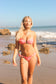 Woman in a pink bikini standing on a beach with ocean waves in the background