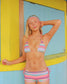 Woman wearing a colorful bikini standing in front of a yellow and blue wall.
